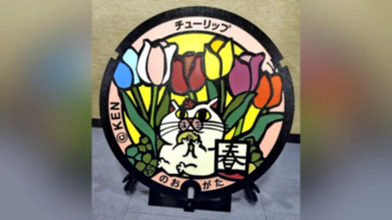 12歳の切り絵クリエイターKENさんがデザインしたネコとチューリップのマンホール蓋が福岡県直方市で完成