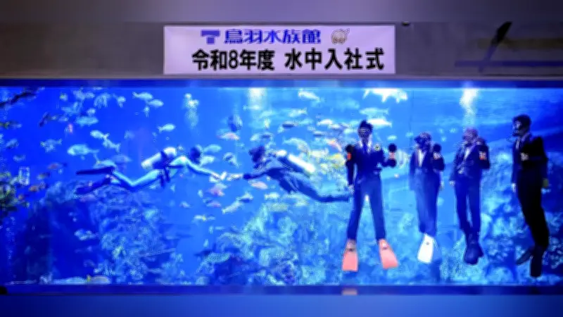 鳥羽水族館で恒例の「水中入社式」、スーツ姿の新入社員が水槽内で辞令書を受け取る